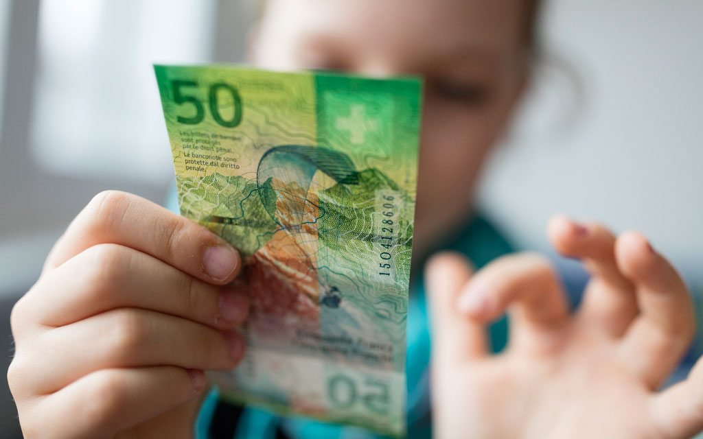 A child examines a 50-franc banknote